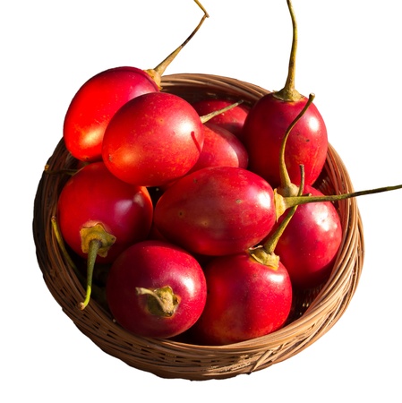 Wicker basket full of Tamarillo s cut out against a white backgroundの写真素材