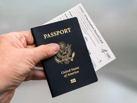 Costa Mesa, CA - March 16, 2021: Mans hand holding Passport and Official Covid-19 Vaccination Record Cardのeditorial素材