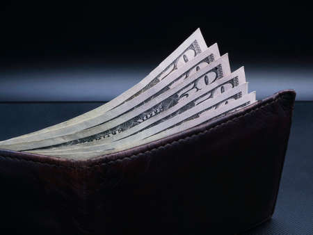 brown leather wallet with money on black backgroundの写真素材