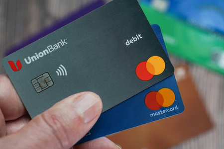 Overhead view of man holding debit and credit cards with more card defocused in background.