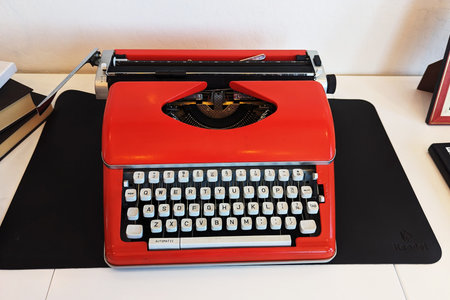 Top view of white desk workplace with bright red vintage typewriterの写真素材