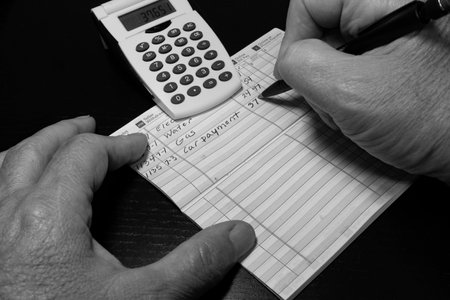 Man making entry in check register with calculator in black and whiteの写真素材