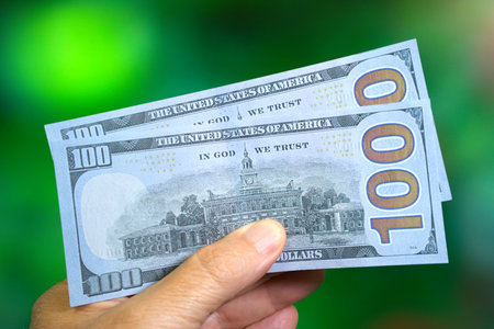 Mans hand holding 200 USD in prop US 100 dollar billsの写真素材