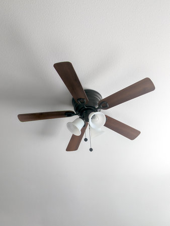 Five blade electric ceiling fan mounted on white ceilingの写真素材
