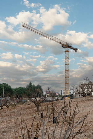 Tall crane at construction site against blue sky with white cloudsの写真素材