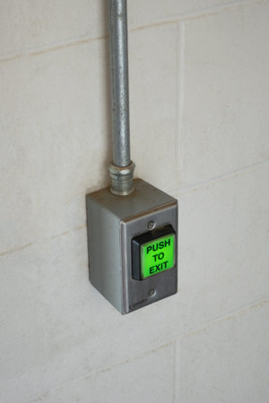 Illuminated green push to exit button on wall