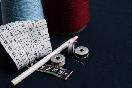 Sewing tools and measuring tape on a dark blue background.の写真素材