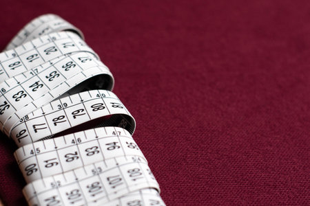 Close up of measuring tape on red background with copy space for text