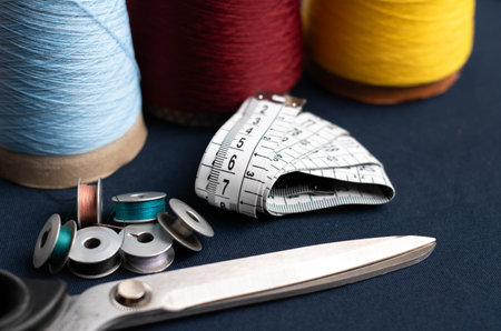 measuring tape, cones of threads with metal scissors on blue fabricの写真素材
