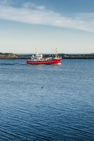 Red fishing cutter on blue water - Lofoten Island.の写真素材