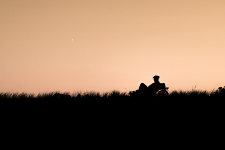 Silhouette of biker riding on sunset.の写真素材