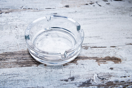 Empty glass ashtray on a wooden table.の写真素材