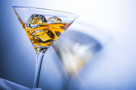Orange liqueur into a martini glass. Multicolored reflections on the background.の写真素材
