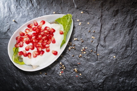 Herring salad in sour cream with pomegranate. It lies on a black stone slab. View from above. Lying flat.の写真素材