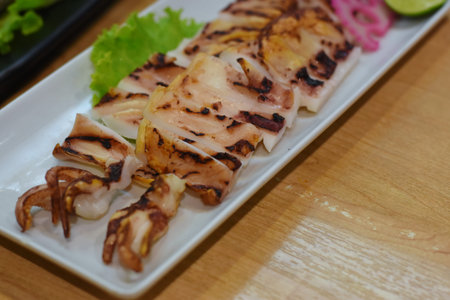 Grilled squid in a white plate on a wooden table. Close-up.