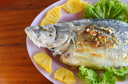 Grilled fish with lemon and lettuce on wooden background.Thai foodの写真素材