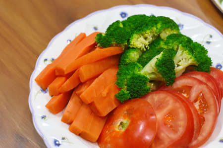 vegetable salad with carrots, broccoli and tomatoes on a plateの写真素材