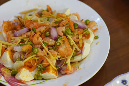 Thai spicy salad with prawns and vegetables on white plateの写真素材