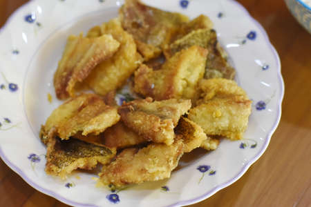 Fried fish in a white porcelain plate on the tableの写真素材
