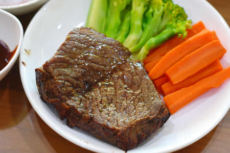 Beef steak with vegetables on wooden table. Close-up.の写真素材