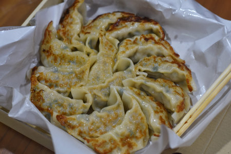 Fried dumplings in a white box with chopsticks.