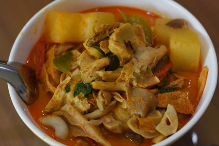 Thai spicy soup with pork in a white bowl on wooden tableの写真素材