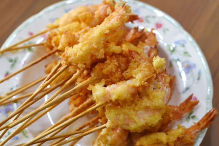 Fried shrimp on wooden skewers on a plate in a restaurantの写真素材