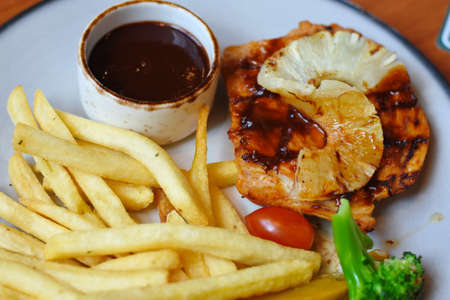 grilled chicken breast with french fries and sauce on white plate.の写真素材