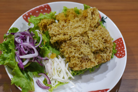 Crispy fried fish with lettuce and onion on the plate.