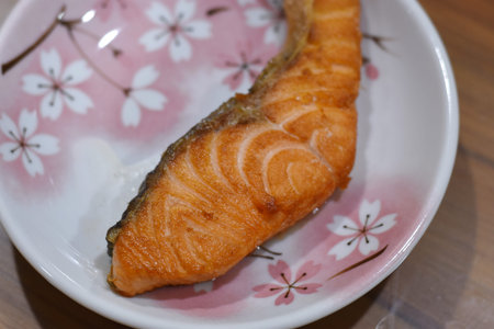 Fried salmon fillet on a plate on a wooden table.