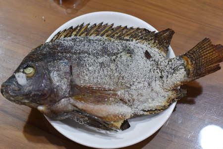 fried fish with salt on a white plate on a wooden table.の写真素材
