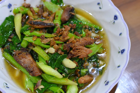 Stir-fried kale with pork in a bowl on the tableの写真素材