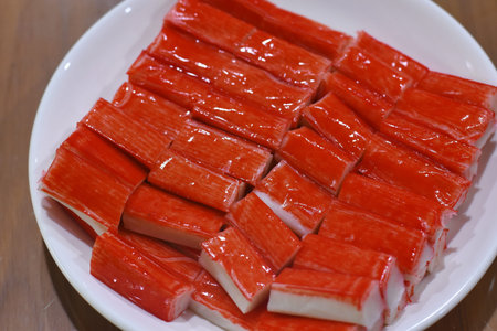 Crab sticks in a plate on a wooden table, close-up