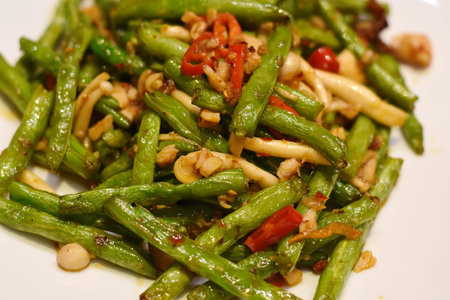 Stir-fried green beans with garlic and chilli on white plate