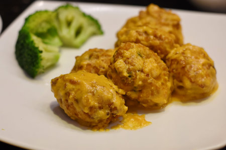 Crispy fried meatballs with curry sauce on a white plate