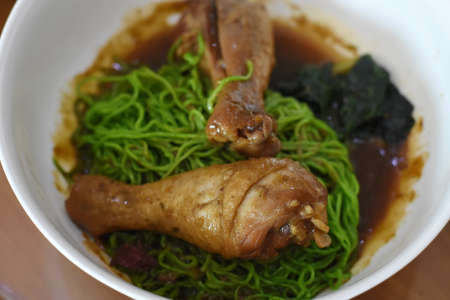 Rice noodle soup with chicken leg in white bowl on tableの写真素材