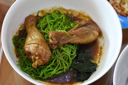 Rice noodle soup with chicken in white bowl on wooden tableの写真素材