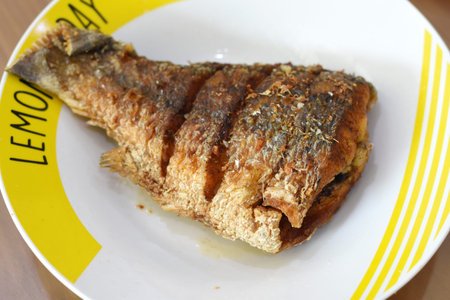Fried fish in a plate on a wooden table close-up