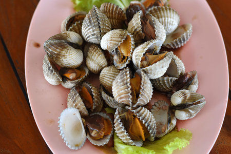 Clams on plate with salad on wooden table, stock photo