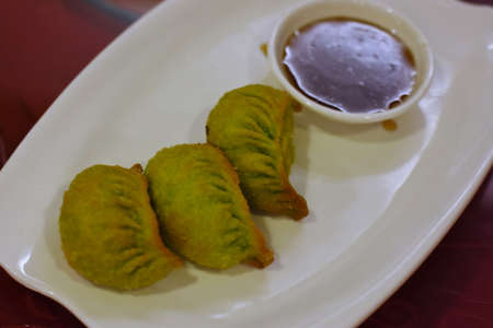 Deep fried dumplings with sweet and sour sauce on white plateの写真素材