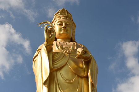 Golden buddha statue with blue sky and white clouds background.の写真素材