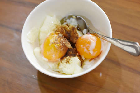 Soft-boiled egg in a white bowl on wooden table.の写真素材
