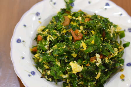 Stir-fried spinach with egg in a plate on the tableの写真素材