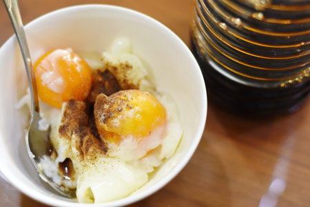 Fried eggs in a white bowl on a wooden table. Close up.の写真素材