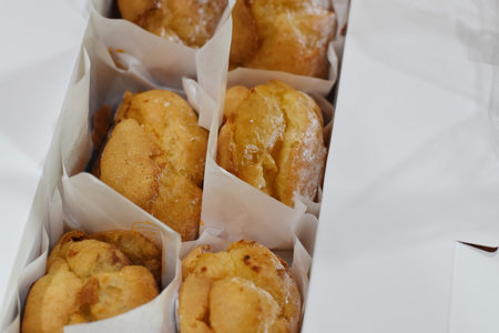 Freshly baked homemade muffins in a paper box on a white background