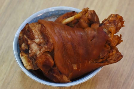 Crispy pork knuckle in a bowl on a wooden tableの写真素材