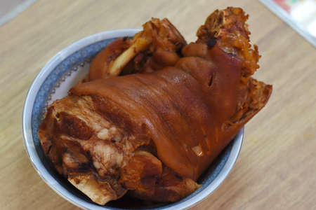 Baked pork knuckle in a bowl on a wooden table.の写真素材