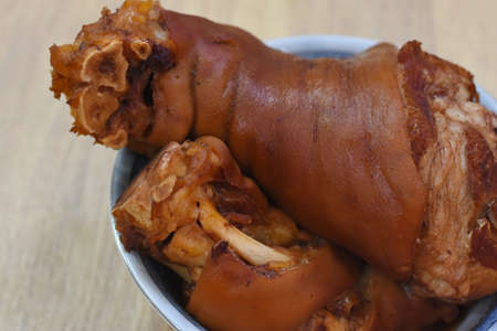 Fried pork knuckle in a metal bowl on a wooden tableの写真素材