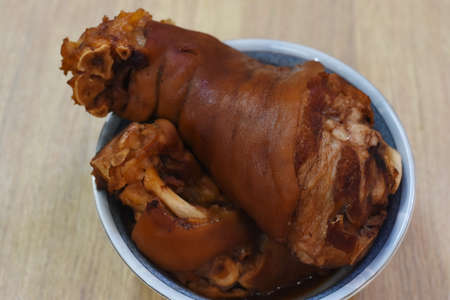 Crispy pork knuckle in a tin can on a wooden tableの写真素材