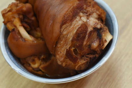 Pork knuckle in a bowl on a wooden table. Close up.の写真素材